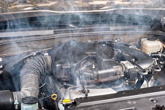 A smokey car engine shows signs of a lack of maintenance.