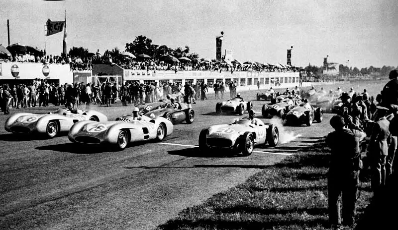 Gro&szlig;er Preis von Italien in Monza, 11.&nbsp;September 1955. Foto vom Start. Vordere Reihe, von links nach rechts: die Mercedes-Benz W&nbsp;196&nbsp;R Formel&nbsp;1-Rennwagen von Juan Manuel Fangio (Stromlinienkarosserie, Startnummer&nbsp;18, der sp&auml;tere Sieger des Rennens), Stirling Moss (Stromlinienkarosserie, Startnummer&nbsp;16) und Karl Kling (Rennwagen mit frei stehenden R&auml;dern, Startnummer&nbsp;20). Im Hintergrund: W&nbsp;196&nbsp;R mit frei stehenden R&auml;dern von Piero Taruffi (Startnummer&nbsp;14, sp&auml;ter Platz&nbsp;2). (Fotosignatur der Archive von Mercedes-Benz Classic: R7963) 

Italian Grand Prix in Monza, 11&nbsp;September 1955. Photo taken at the start of the race. Front row, from left to right: Mercedes-Benz W&nbsp;196&nbsp;R Formula&nbsp;1 racing cars of Juan Manuel Fangio (streamlined bodywork, starting number&nbsp;18, the eventual winner of the race), Stirling Moss (streamlined bodywork, starting number&nbsp;16) and Karl Kling (racing car with free-standing wheels, starting number&nbsp;20). In the background: W&nbsp;196&nbsp;R with free-standing wheels of Piero Taruffi (starting number&nbsp;14, eventually placing 2nd). (Photo index number in the Mercedes-Benz Classic Archive: R7963)