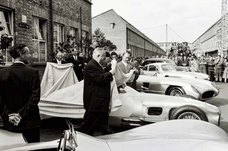 Abschlussfeier der Rennsaison 1955 im Mercedes-Benz Werk Untertürkheim am 24. Oktober 1955. Mercedes-Benz Rennleiter Alfred Neubauer breitet nach dem Rückzug aus dem Motorsport weiße Tücher über die Mercedes-Benz Rennwagen. Hier am W 196 R mit frei stehenden Rädern zusammen mit Juan Manuel Fangio, dem Formel 1-Weltmeister 1955. (Fotosignatur der Archive von Mercedes-Benz Classic: 55302-17)  

Closing ceremony of the 1955 racing season at the Mercedes-Benz plant in Untertürkheim on 24 October 1955. Mercedes-Benz racing director Alfred Neubauer spreads white cloth covers over the Mercedes-Benz racing cars after their withdrawal from motorsport. Here next to the W 196 R with free-standing wheels, together with Juan Manuel Fangio, the 1955 Formula 1 World Champion. (Photo index number in the Mercedes-Benz Classic Archive: 55302-17)