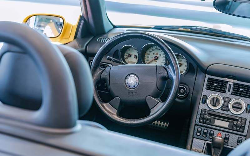 Mercedes-Benz SLK 230 Kompressor der Baureihe R 170 in der Lackierung yellowstone (Mercedes-Benz Farbcode 685) aus dem Jahr 1996. Detailaufnahme des Cockpits in der Sonderausstellung „Youngtimer“ des Mercedes-Benz Museums, 2025. Foto: Thomas Niedermüller. (Fotosignatur der Archive von Mercedes-Benz Classic: D854702) 

Mercedes-Benz SLK 230 Kompressor R 170 painted in yellowstone (Mercedes-Benz colour code 685) from the year 1996. Detailed view of the cockpit in the special “Youngtimer” exhibition at the Mercedes-Benz Museum, 2025. Photo: Thomas Niedermüller. (Photo index number in the Mercedes-Benz Classic Archives: D854702)